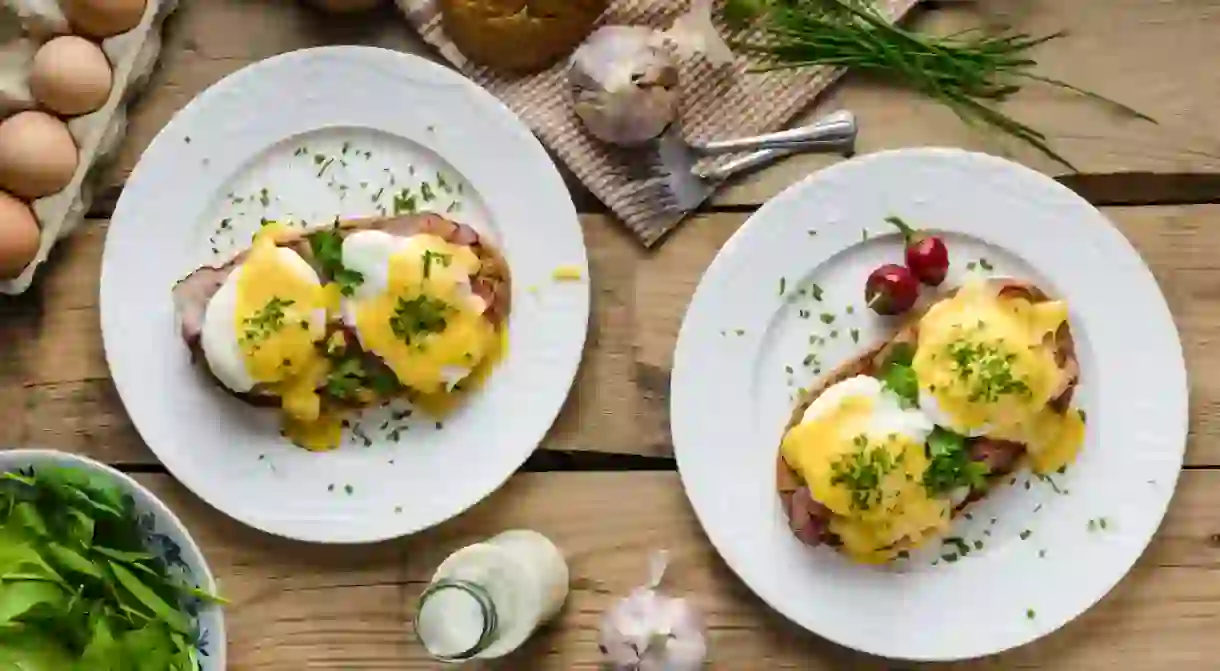 Eggs Benedict with little salad, milk and fresh herbs