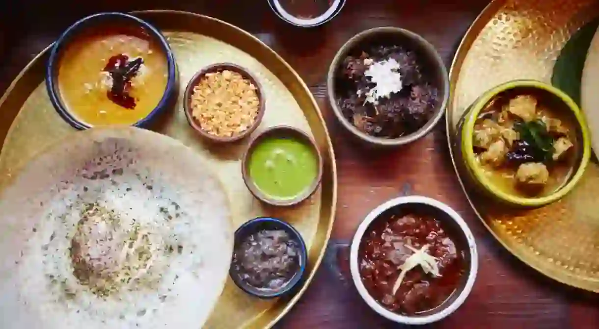 Fish Kari, Black Pork Kari, Lamb Kari and Red Pumpkin Kari with Pol Sambol, Seeni Sambol, Coriander Chutney on plate