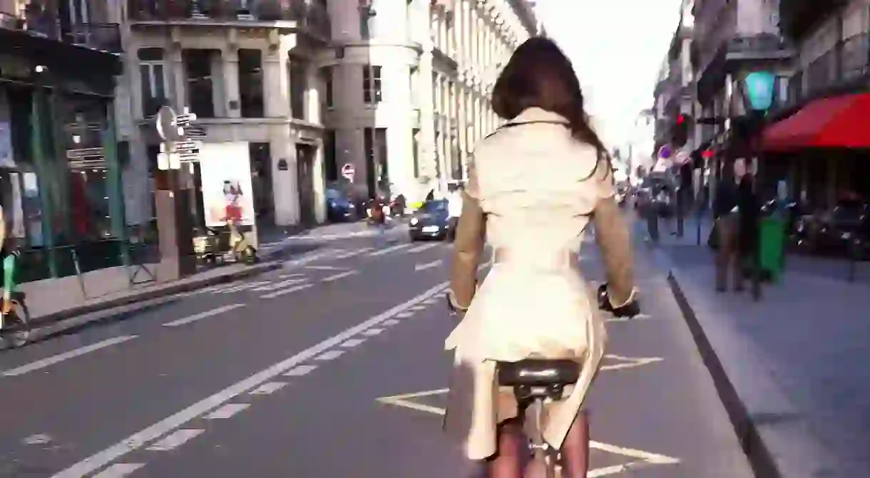 Stylish woman riding a bicycle down a Paris street │