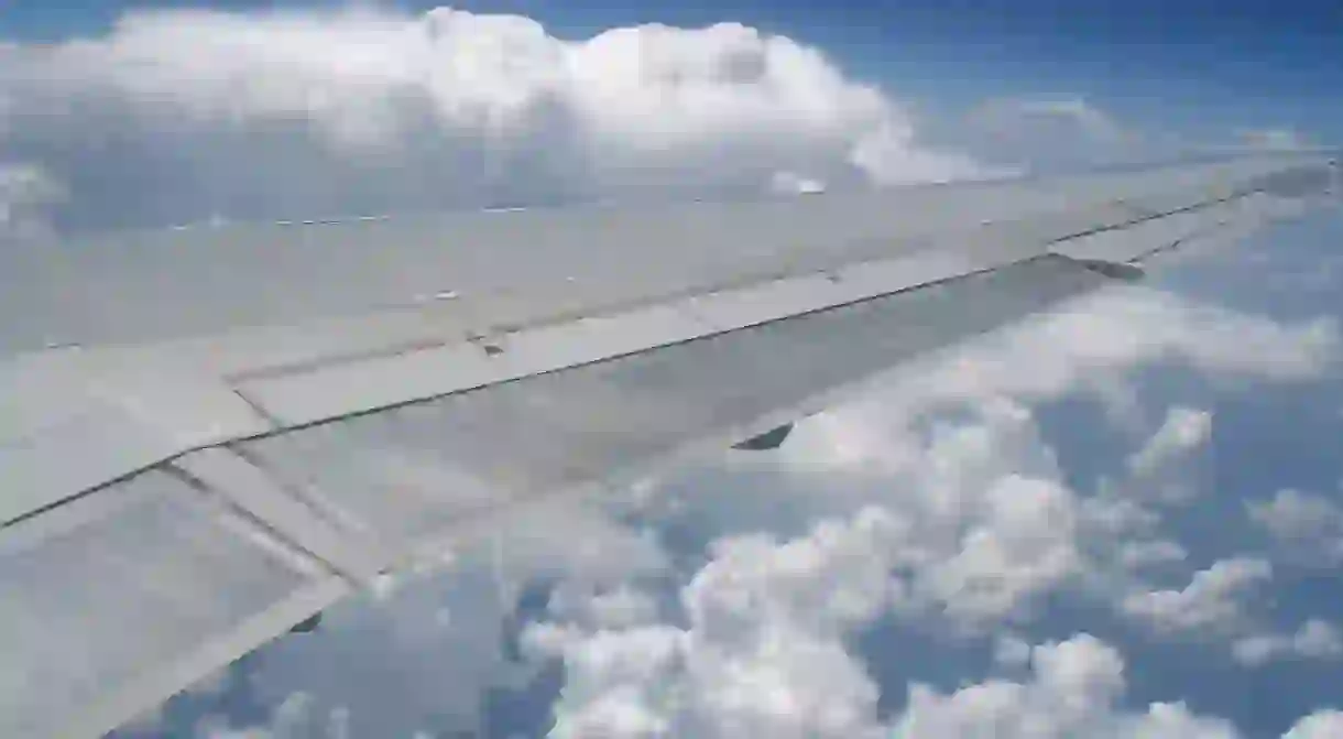 Airplane wing in front of cumulus clouds