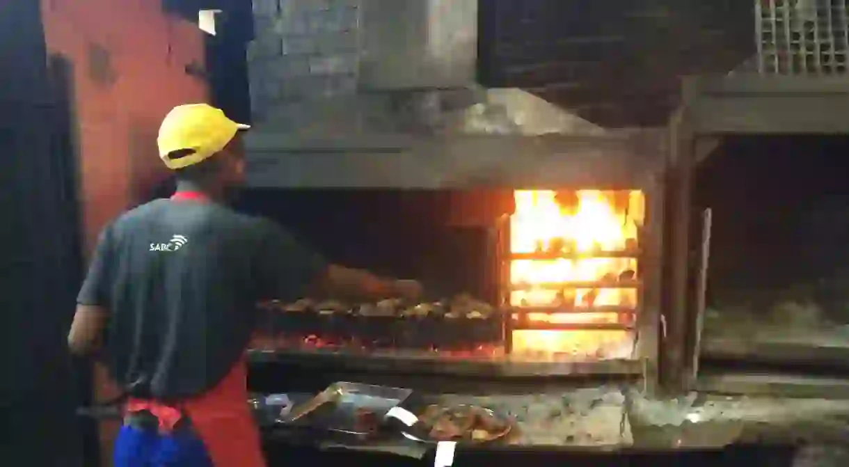 A staff member at Mzolis Place braais meat for patrons in Gugulethu township