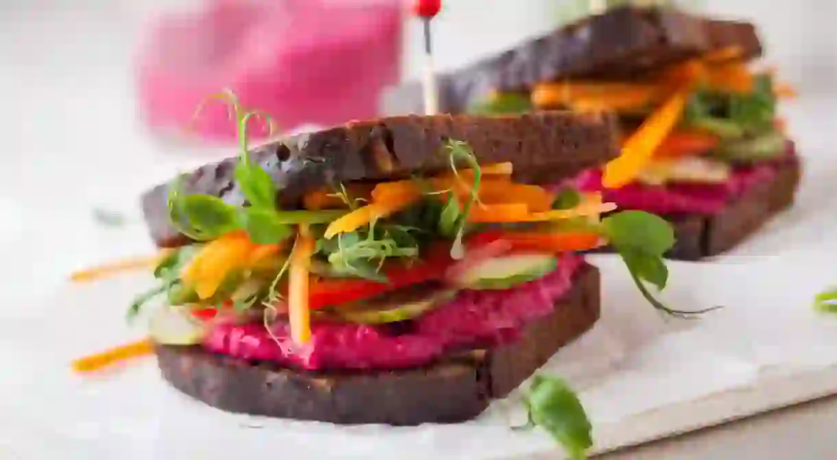 Gluten-free vegan sandwiches with beet hummus, raw vegetables and sprouts