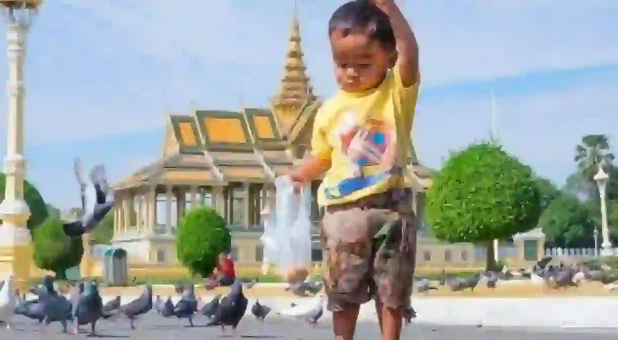 A child feeds the pigeons that gather outside the Silver Pagoda 