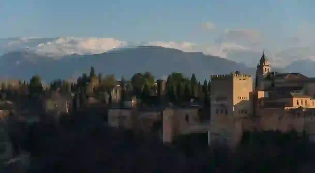 Alhambra Palace in Granada, Spain with Sierra Nevada mountains in snow at the background