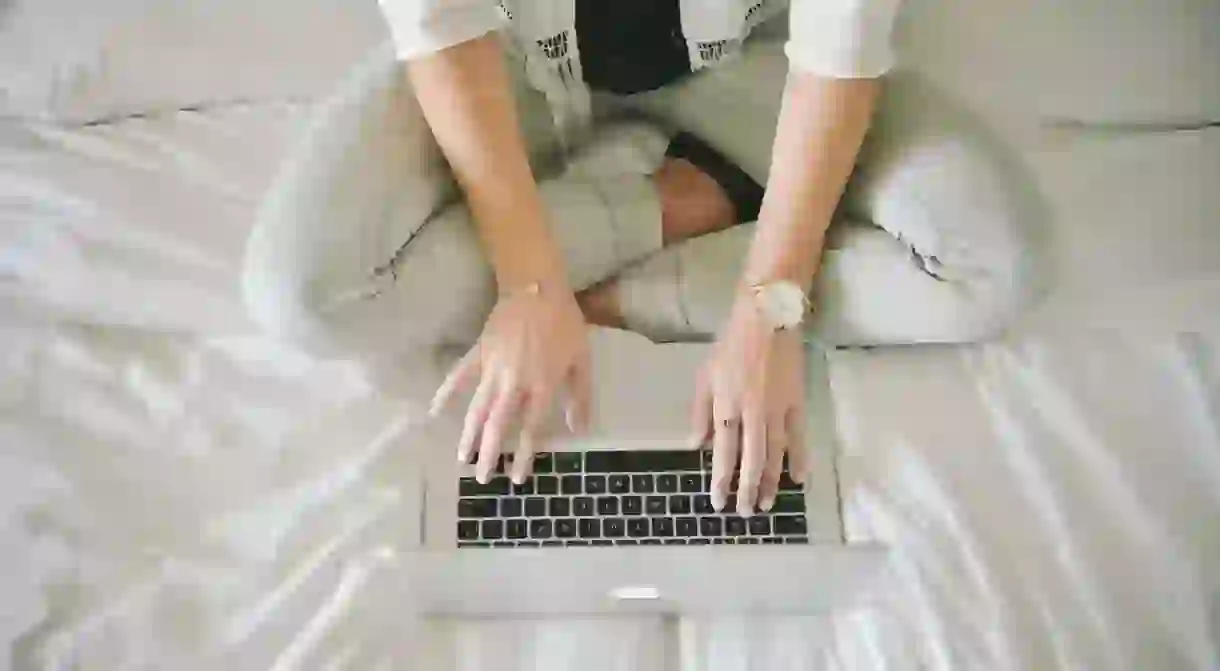 A blogger sitting cross-legged at a laptop