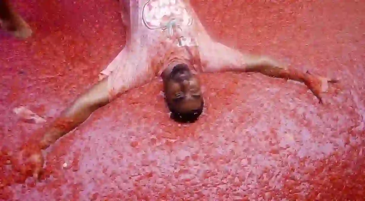 A person lies in a slush of tomatoes during the Tomatina festival in the Valencian village of Bunol, Spain