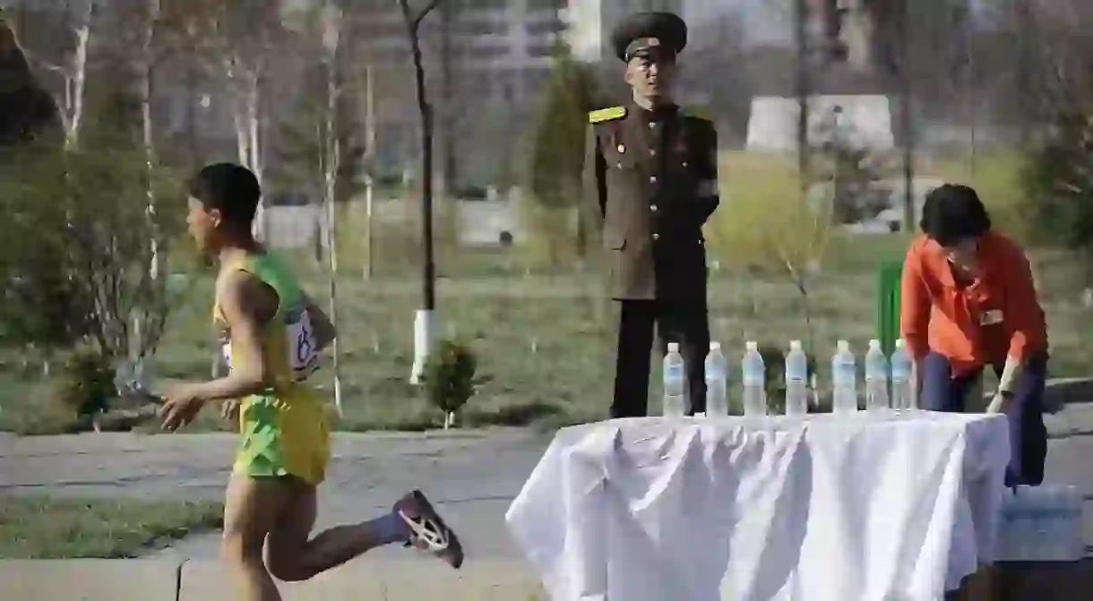 A soldier stands guard as runners pass during the 2017 Pyongyang Marathon