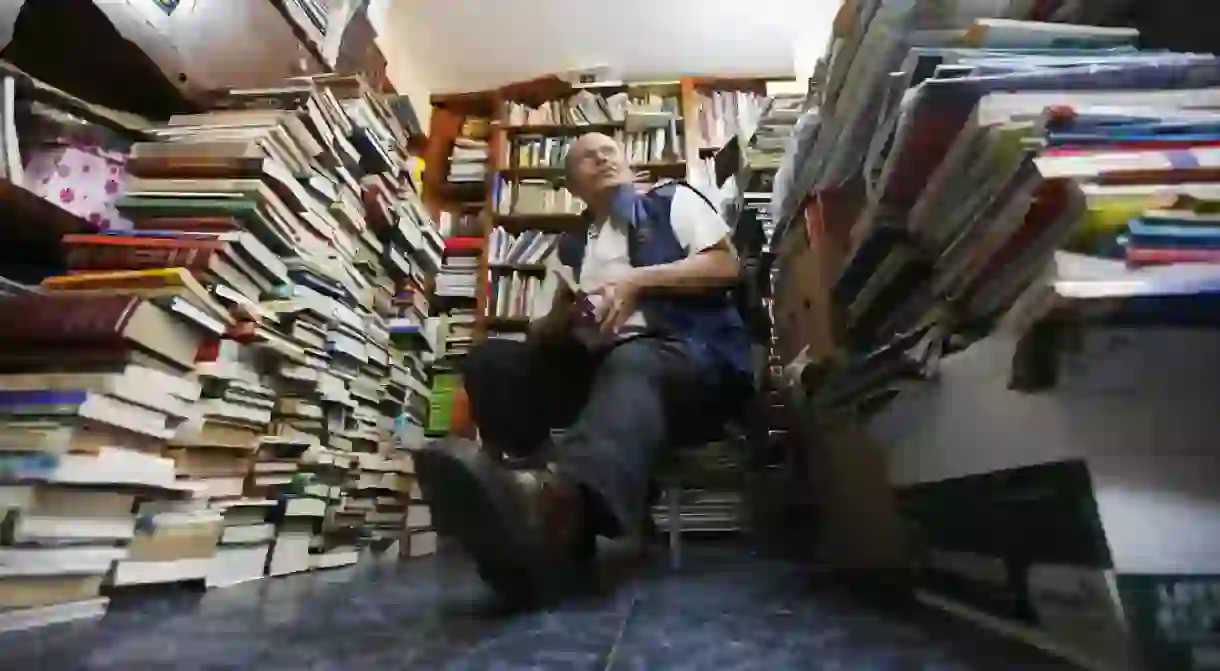 Jose Alberto Gutierrez sits among piles of books at his home in Bogota, Colombia