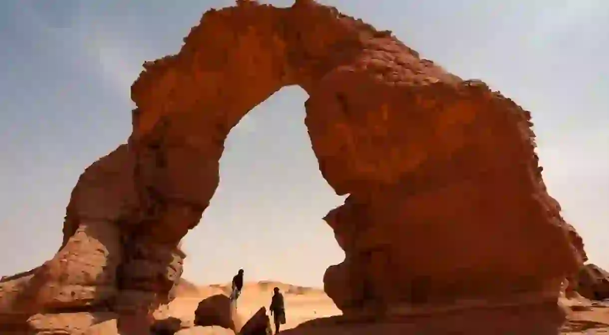 Tuaregs under a stone arch in the Tadrart Acacus in southwest Libya, part of a mountain range which stretches into Algeria