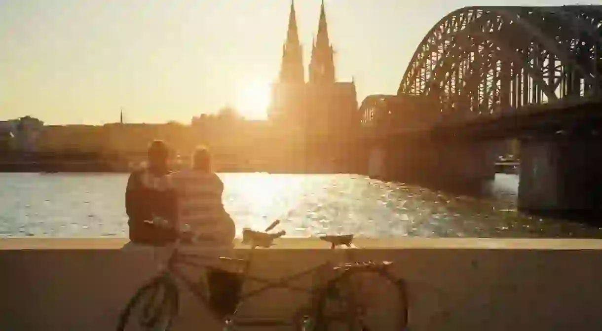 A young couple watches the sun set over Cologne Cathedral