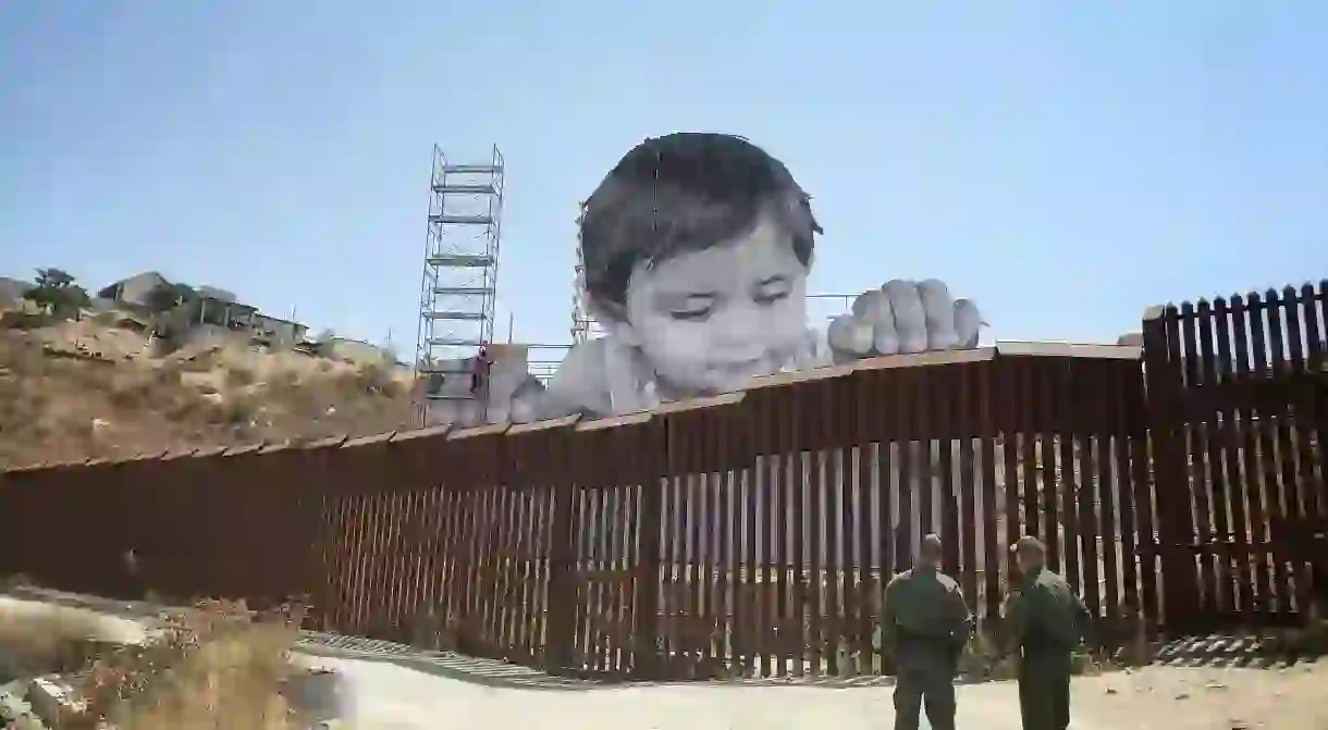 JRs portrait of Kikito peering over U.S. / Mexico border