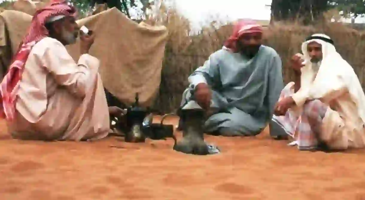 Men drinking karak out of traditional Emirati teapots