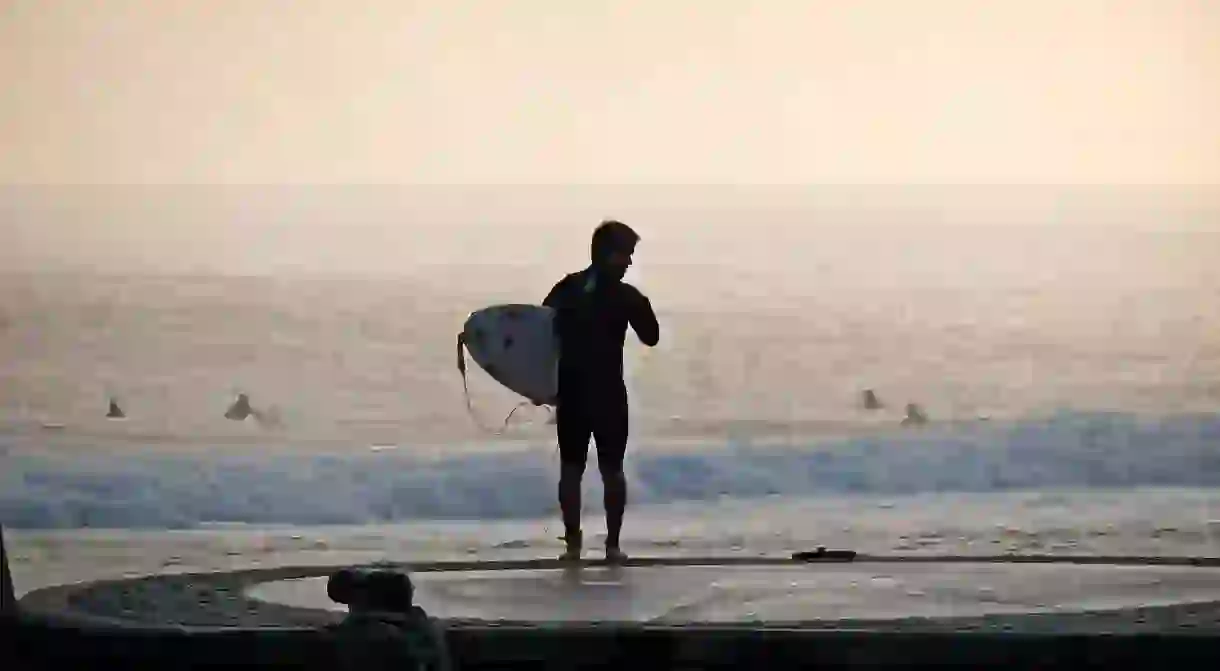 An early surfer catches the wave on Mundaka beach in the Basque Country