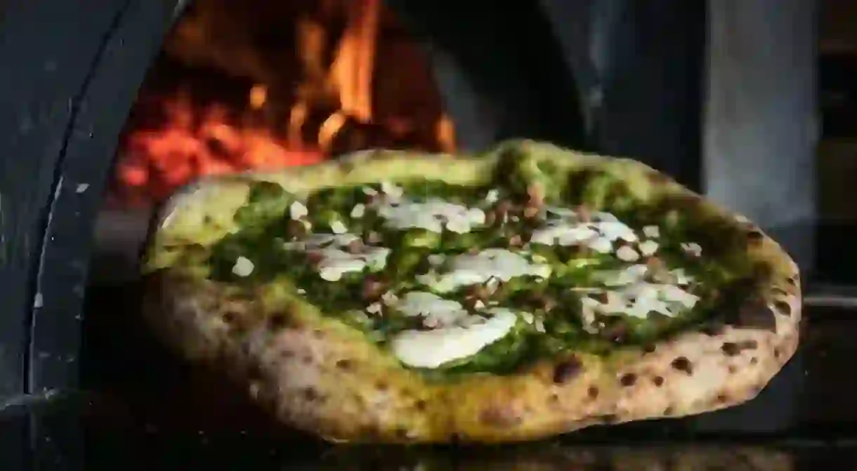 Pizza topped with pesto and freshly chopped nuts