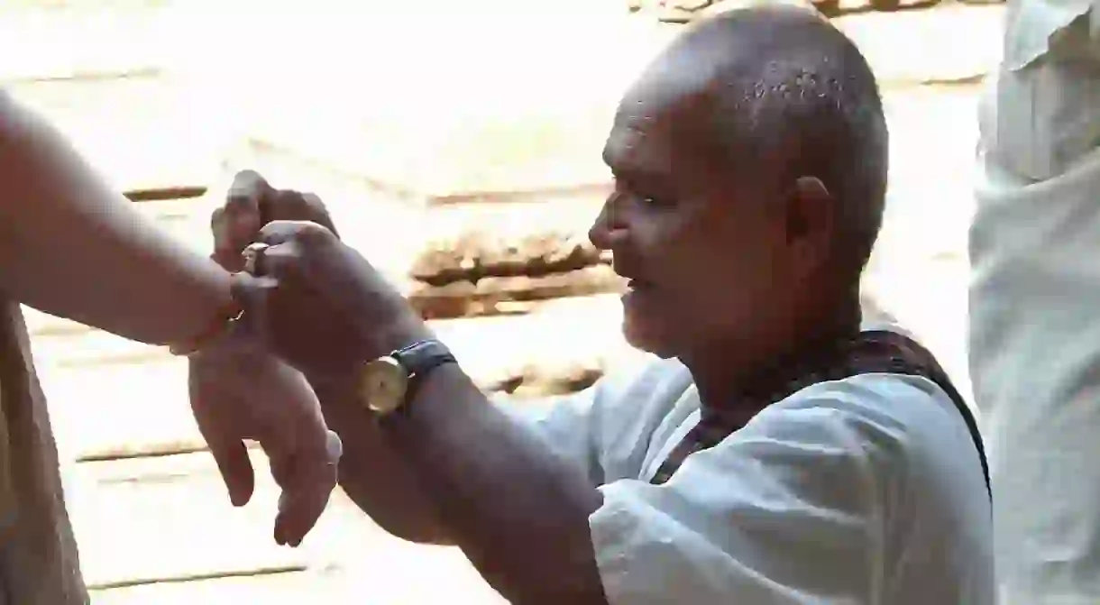 Monk ties thread around a tourists wrist