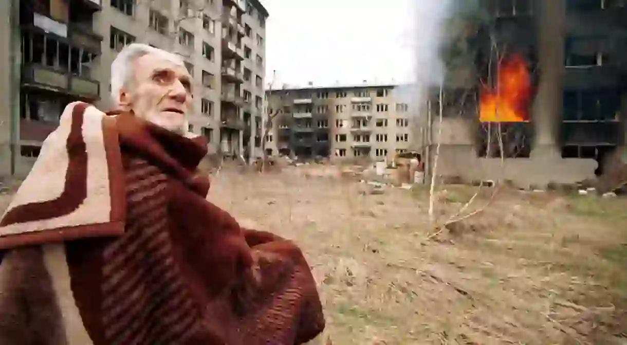 A Bosnian Croat man sits stunned and scared outside his burning home after rampaging Bosnian Serbs looted and set fire to his home in the final hours of siege on Mar 17, 1996 in Sarajevo, Bosnia