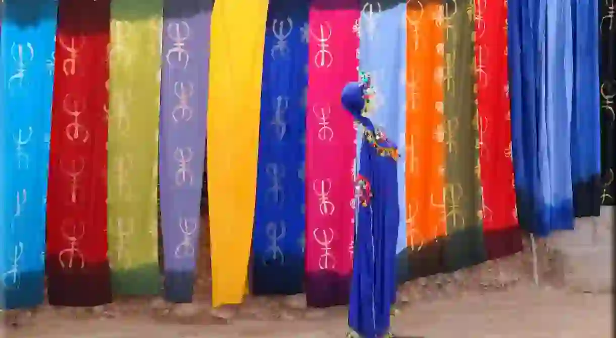 Mannequin wearing traditional Berber attire in front of Berber symbols