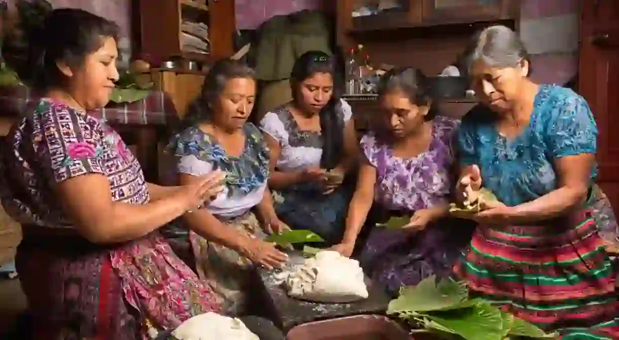 Tzutujil mayan women preparing traditional food together, Guatemala