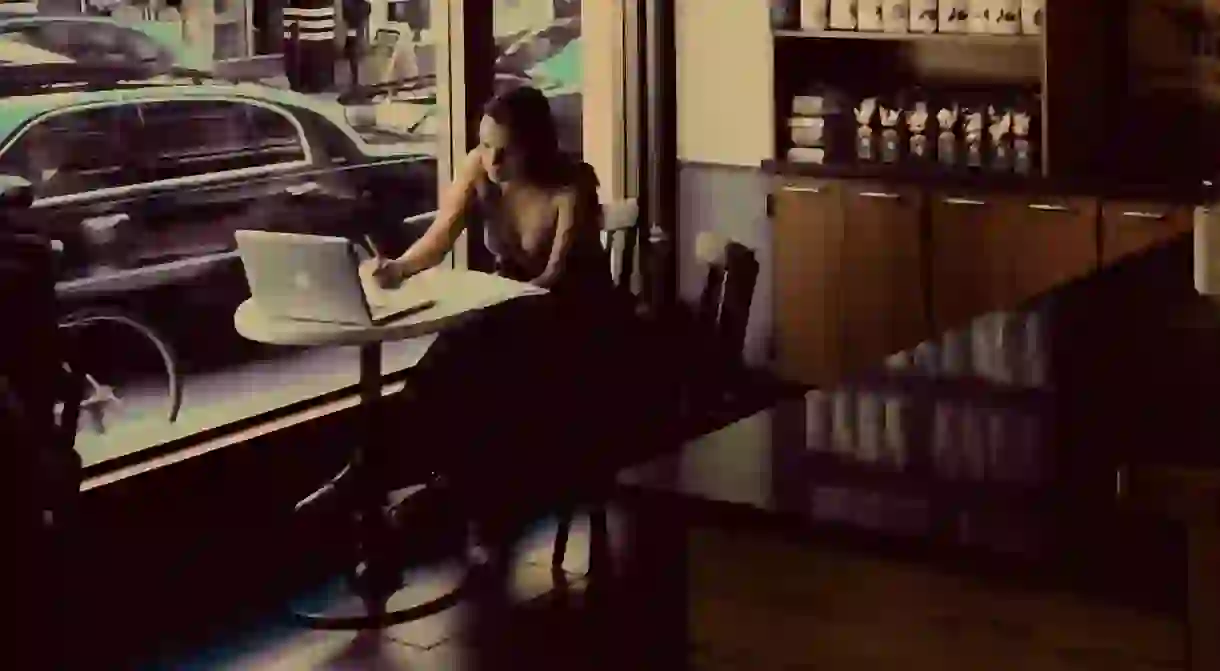 Girl writing in coffee shop.