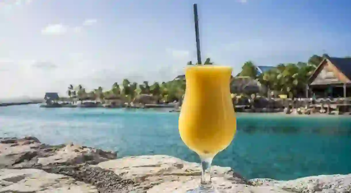 A glass of smoothie on the beach against the sky