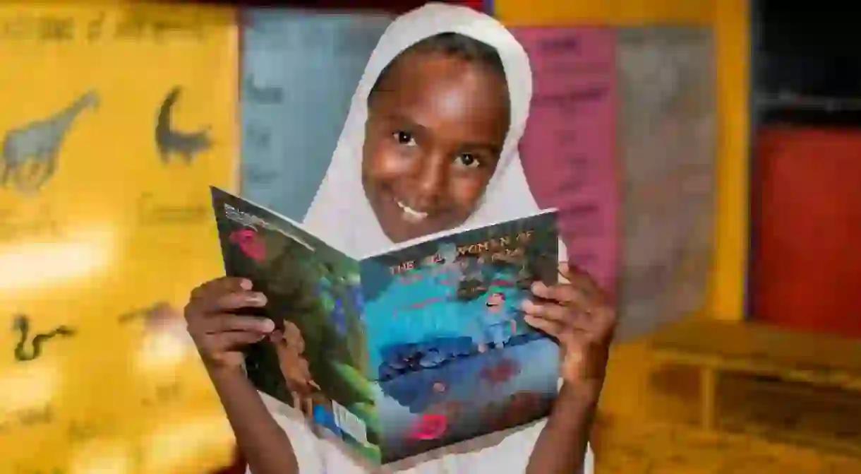 A Ugandan girl with a childrens book written by Ugandan authors