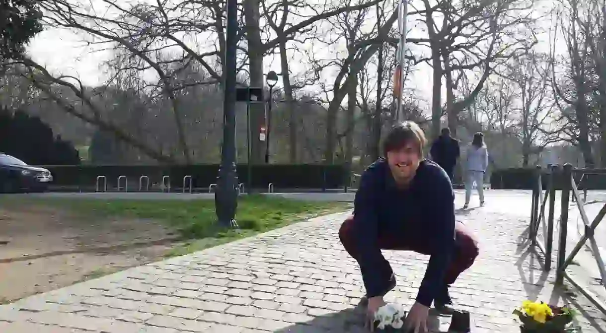 Guerrilla gardener Anton Schuurmans planting flowers in a pothole on a city road in Brussels