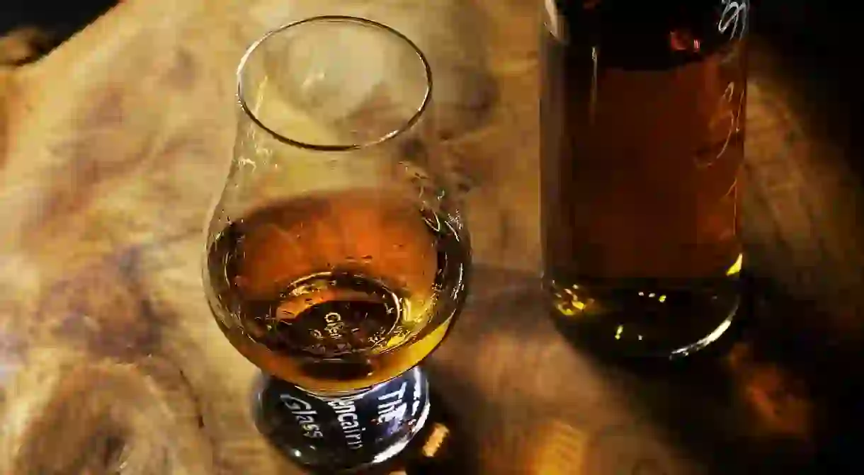 Glass of whiskey on a wooden table.