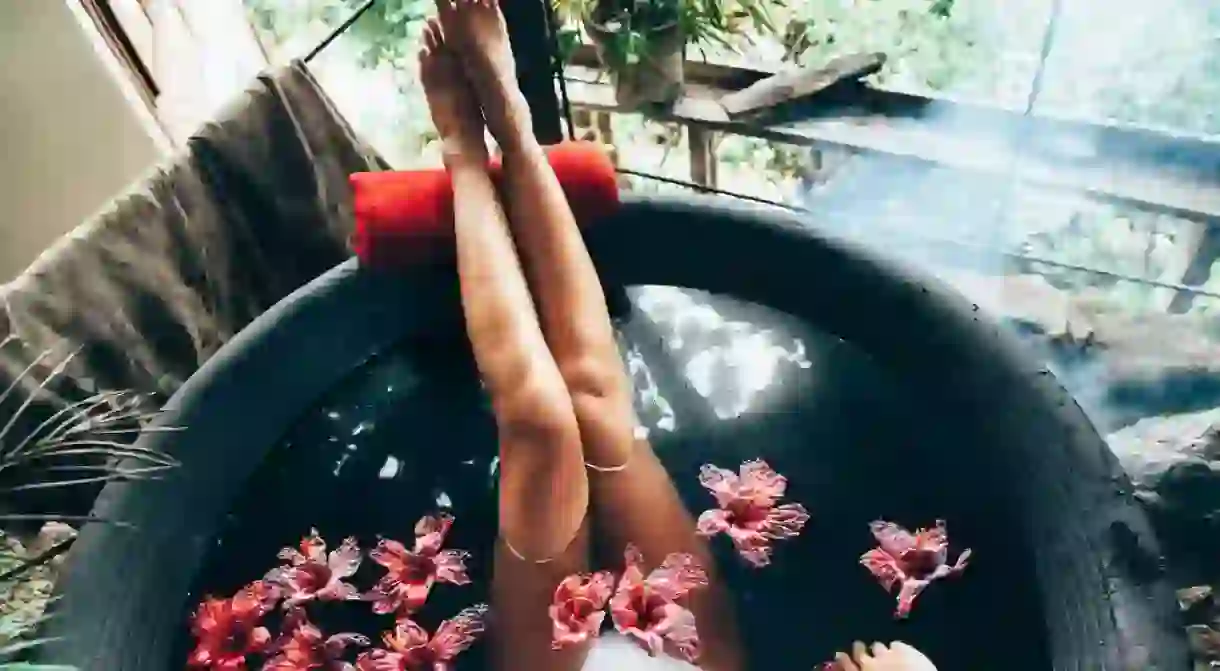 Woman relaxing in round outdoor bath with tropical flowers