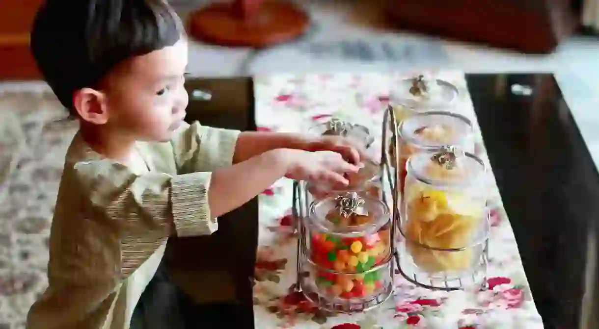 Young child taking Hari Raya snacks from jar