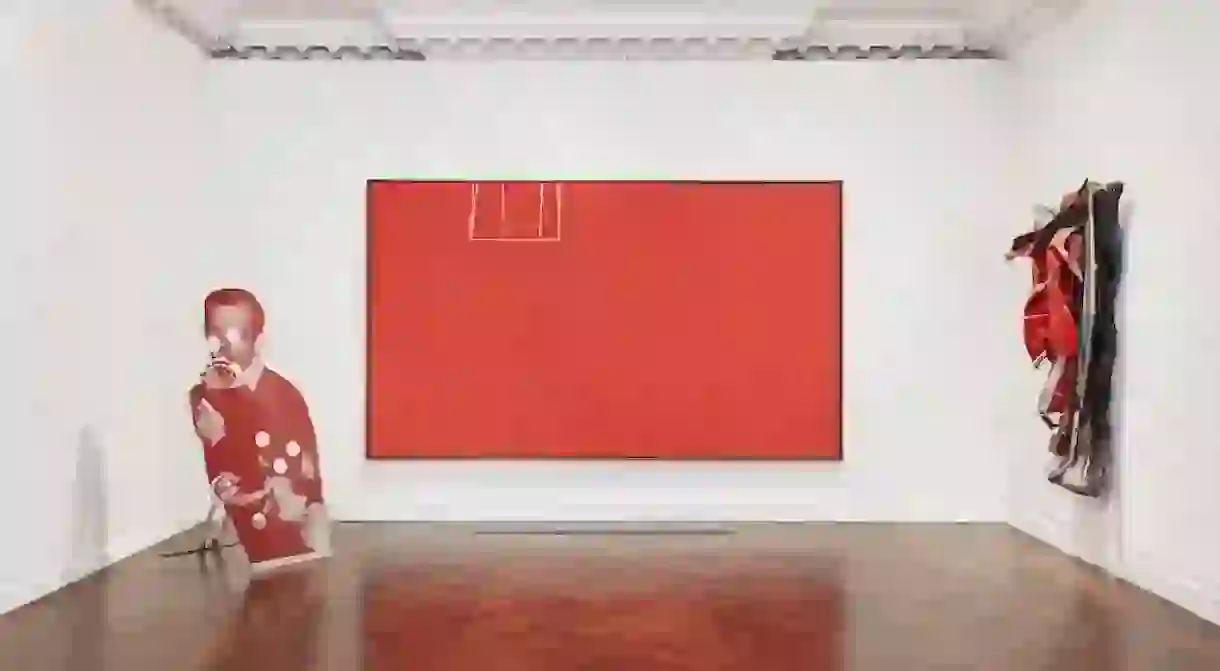 Installation view of Reds, featuring Cady Nolands Bluewald (1989) on the left, Robert Motherwells Open No. 153: In Scarlet with White Line (1970) in the center, and John Chamberlains Funn (1978) on the right