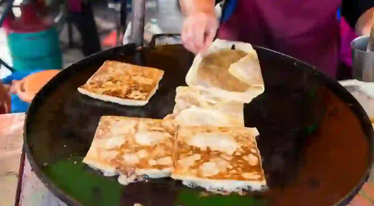 Vendor preparing traditional murtabak cuisine at street bazaar in Malaysia