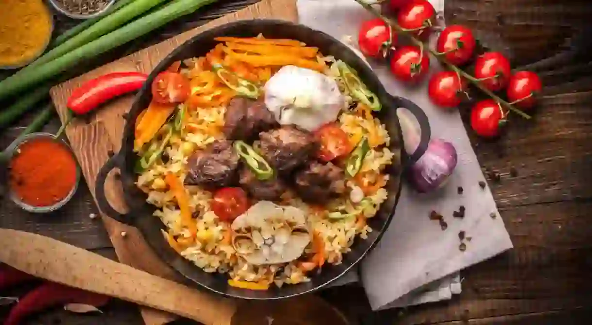 Homemade Uzbek pilaf from lamb served in cast iron cookware