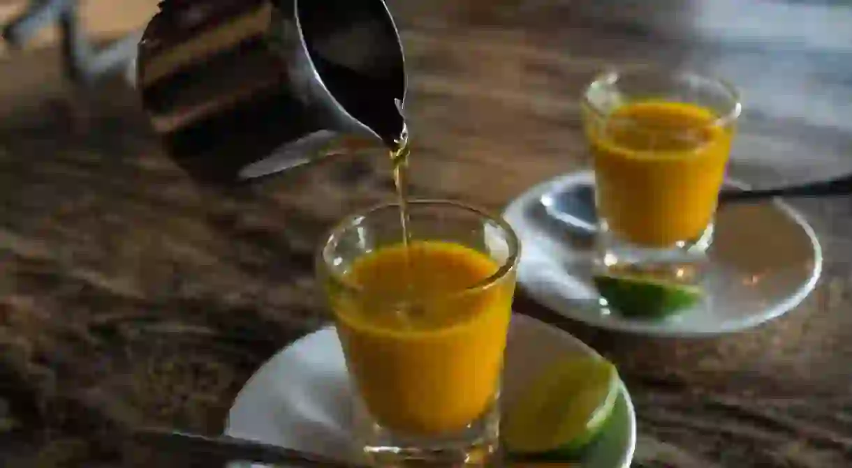 Adding honey to two healthy jamu shots in close-up