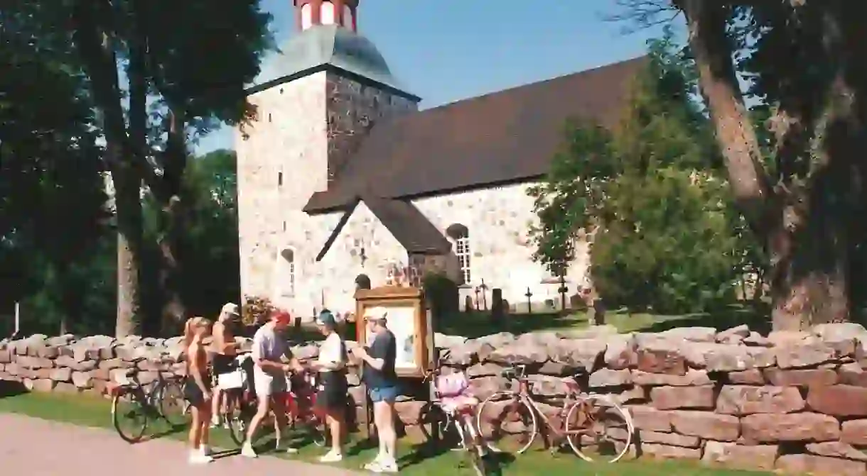 Cyclists stop at Saltvik Church on the Finland Archipelago