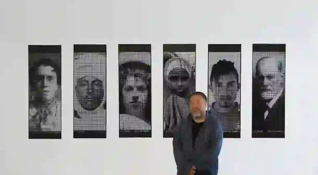 Artist Ai Weiwei stands in front of artworks Banner 51, Banner 2, Banner 13, Banner 200, Banner 90, and Banner 50