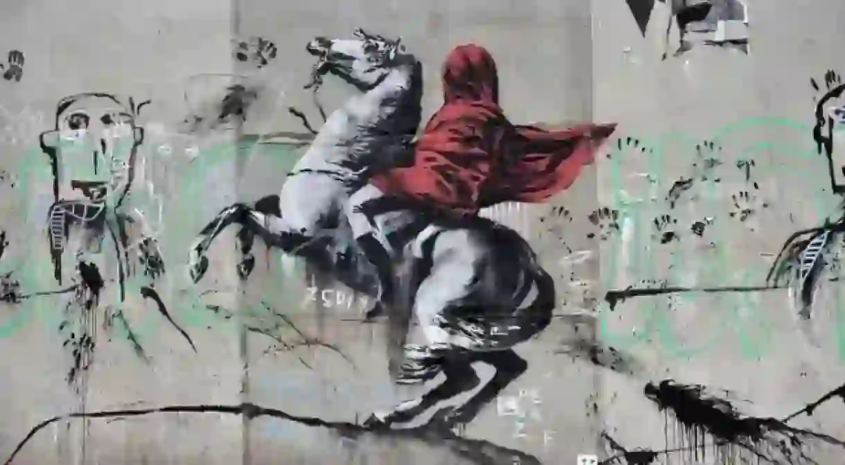 People walk by a recent artwork believed to be attributed to Banksy showing Napoleon rearing his horse, wrapped in a red cloak in the 19th district of Paris, France, June 26, 2018. Several artworks attributed to the anonymous British street artist appeared in the French capital over the last few days. Banksy street art in Paris, France - June 26, 2018