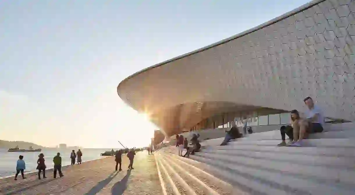 Waterfront steps and curvaceous facade with visitors. MAAT, Lisbon, Portugal