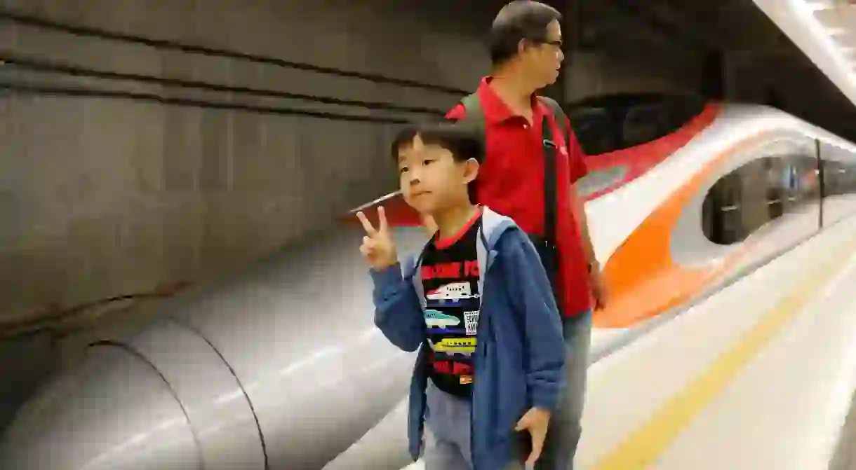 A boy poses with an Express Rail train at the West Kowloon Terminus