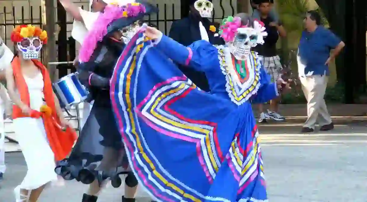 A woman dances during the La Villita parade dressed as a calavera catrina