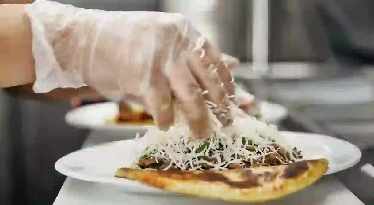 A chef sprinkles cheese on an arepa