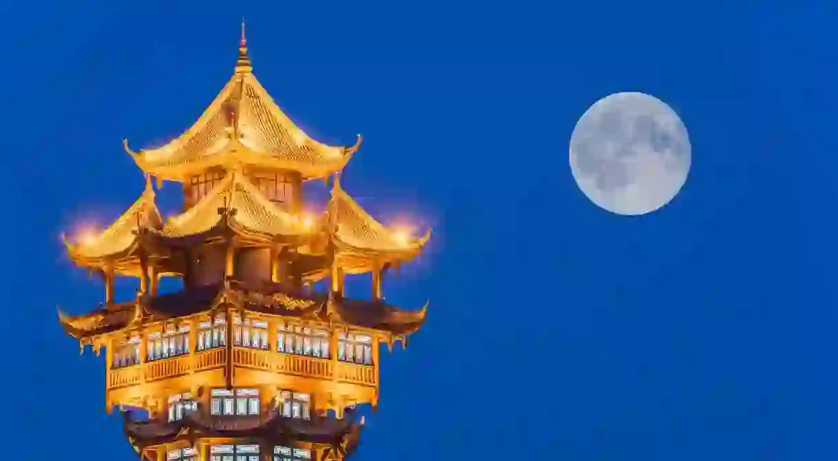 Chengdu’s Jiutian tower stands illuminated under the original, natural moon