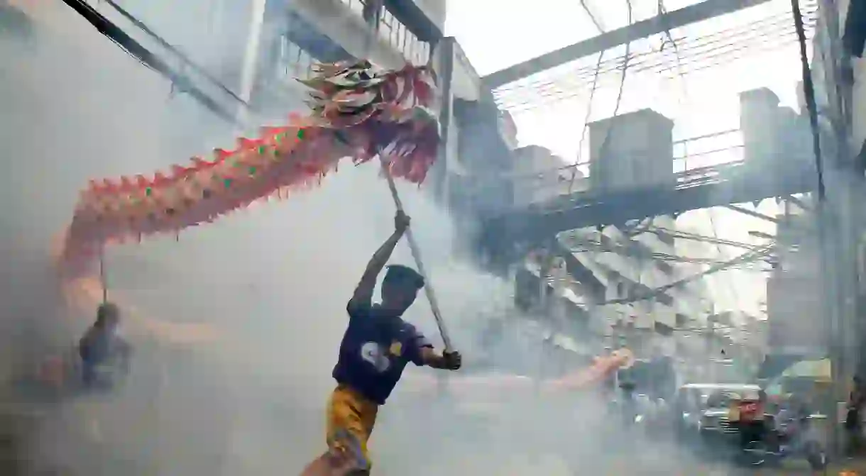 Street performers carry their dragon around firecrackers in Chinatown, Manila