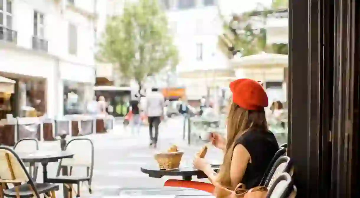 A woman enjoys a French breakfast at a café