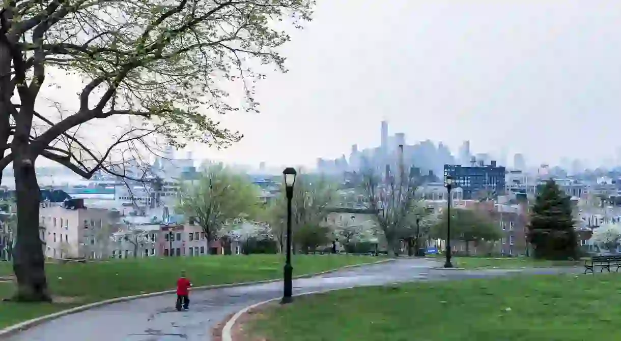 A little boy rides his bike in Sunset Park in Brooklyn with Manhattan views