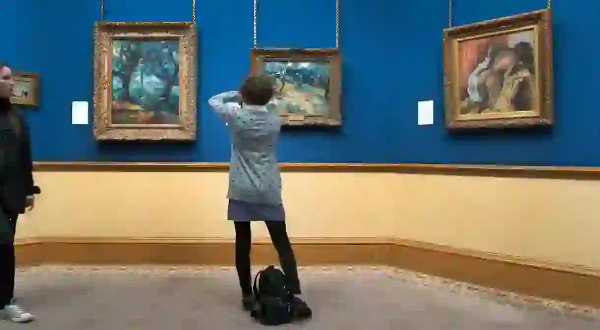 A visitor photographs Vincent Van Gogh’s ‘Olive Trees’ (1889) at the National Gallery of Scotland