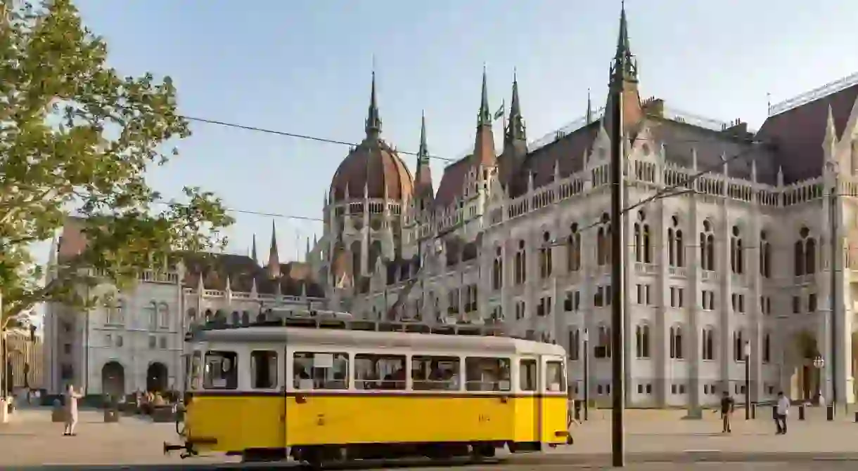 A classic tram rides past the Hungarian Parliament building in Budapest