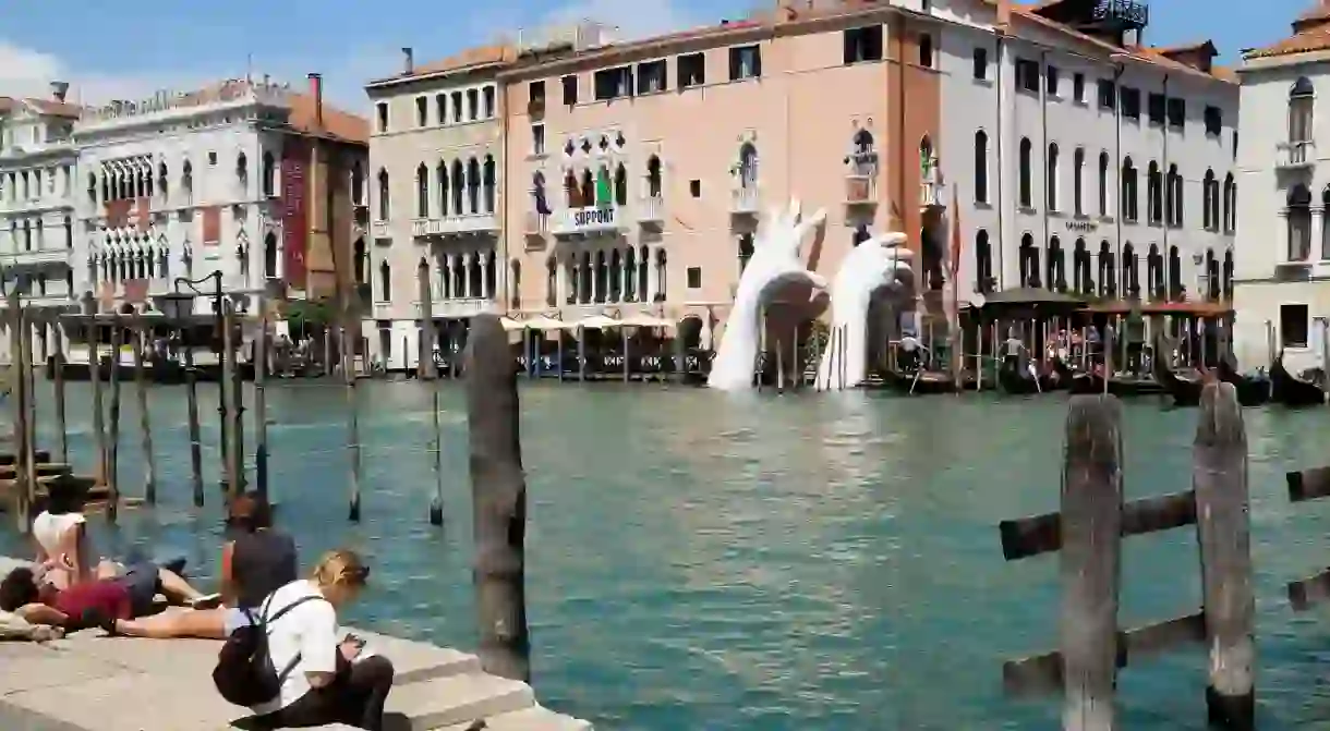 The contemporary sculpture of giant hands by Lorenzo Quinn emerges from Grand Canal during the 2017 Venice Biennale