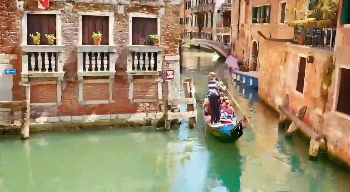 Tourists explore the canals of Venice by gondola