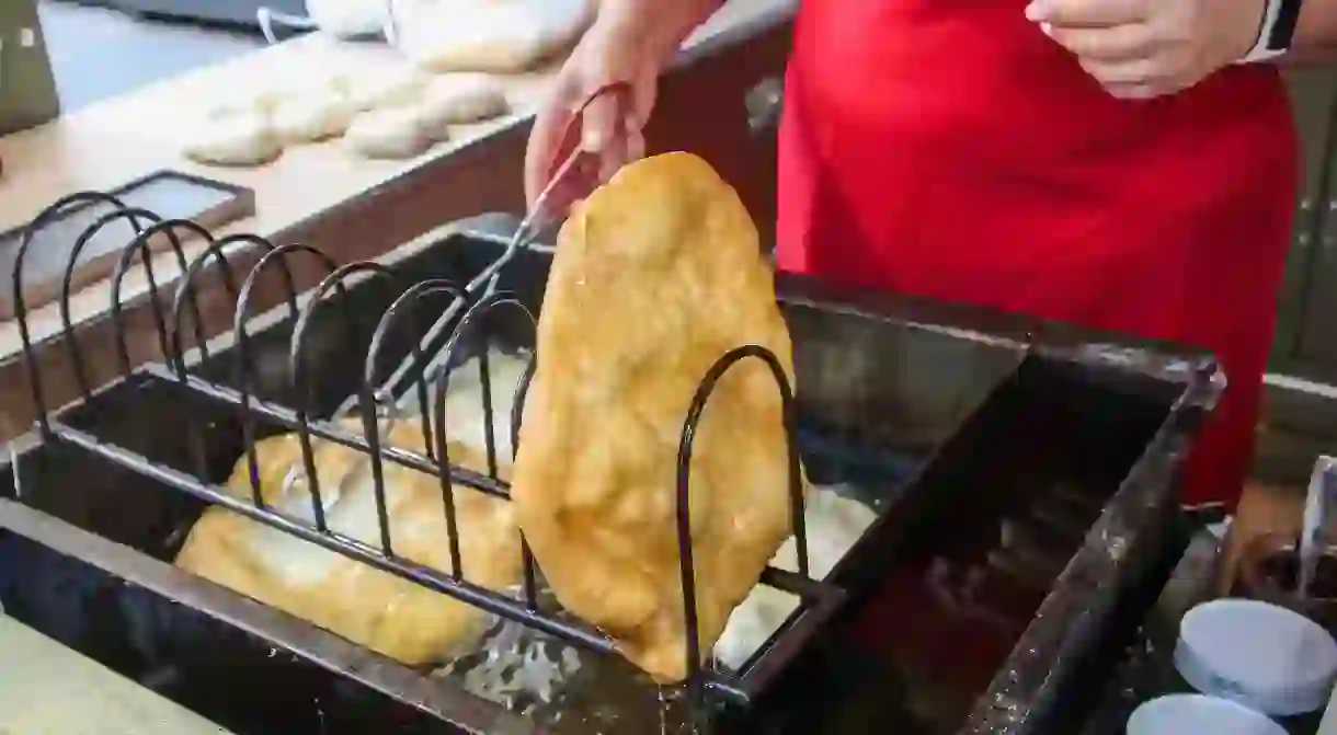 Lángos is fried and typically served with sour cream and grated cheese