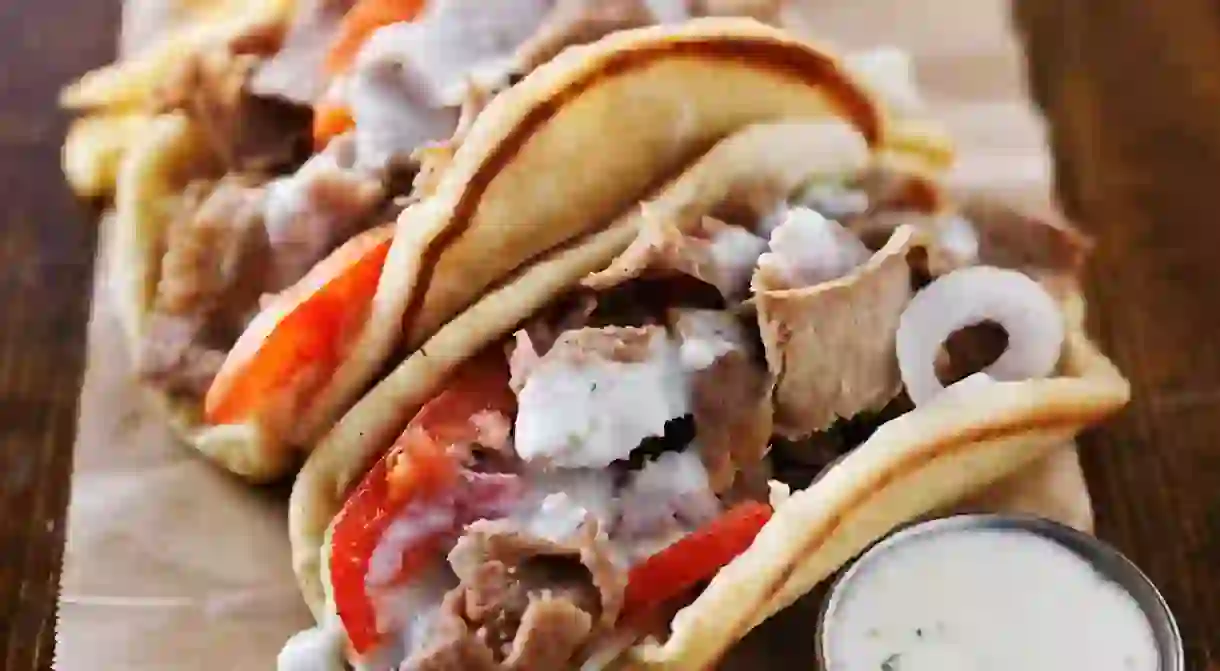 greek gyros with tzatziki sauce and fries on parchment paper. Shot with selective focus in natural light.